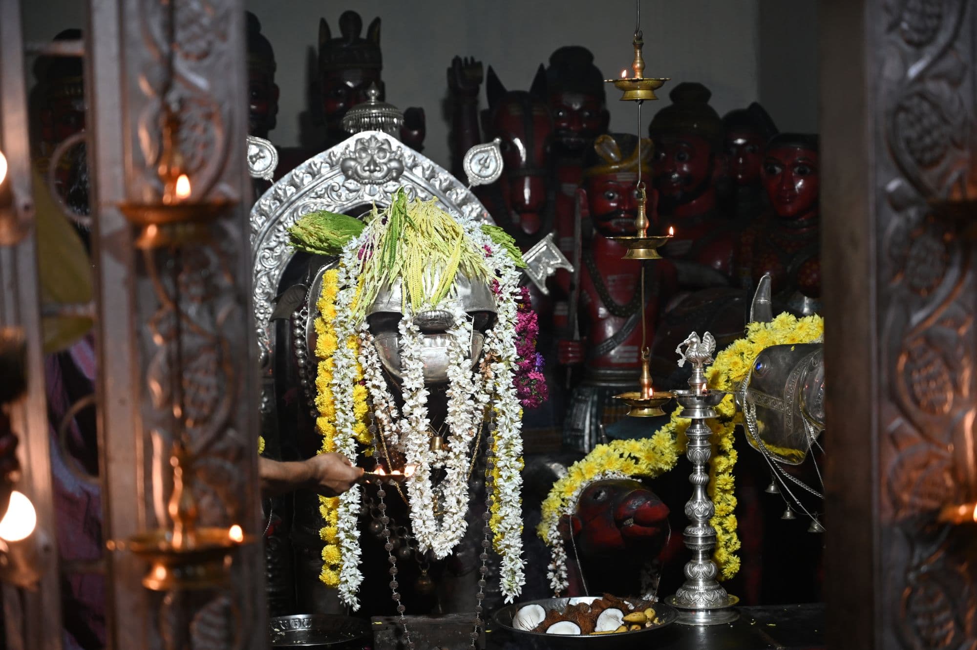 Sri Nandikeshwara deity adorned with flower garlands and ceremonial lamps at Mekkekattu Temple